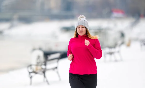 Dívka na sobě sportovní a běží na sněhu v zimě — Stock fotografie