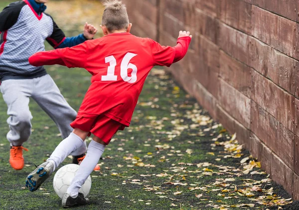 Chicos pateando pelota de fútbol en el campo de deportes —  Fotos de Stock