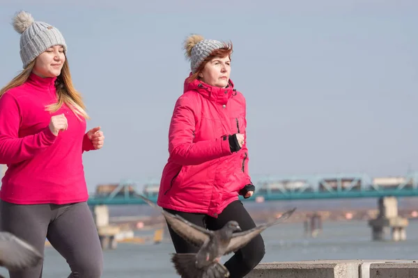 Matka a dcera nosí sportovní oblečení a běží na větrný den — Stock fotografie