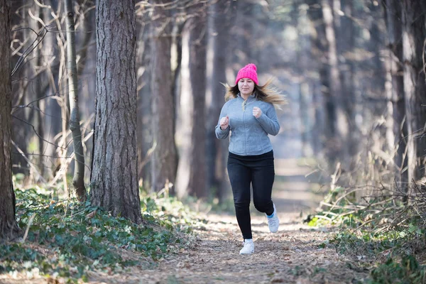 Tyttö yllään urheiluvaatteet ja käynnissä metsässä vuorella — kuvapankkivalokuva