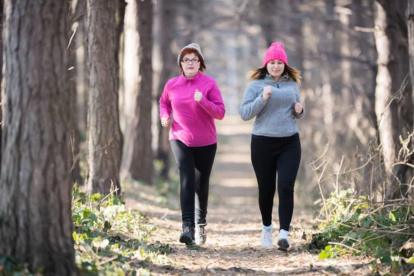 Matka a dcera nosí sportovní oblečení a běh v lese na — Stock fotografie