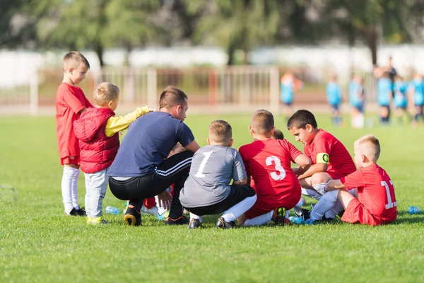 Niños fútbol esperando con el entrenador — Foto de Stock