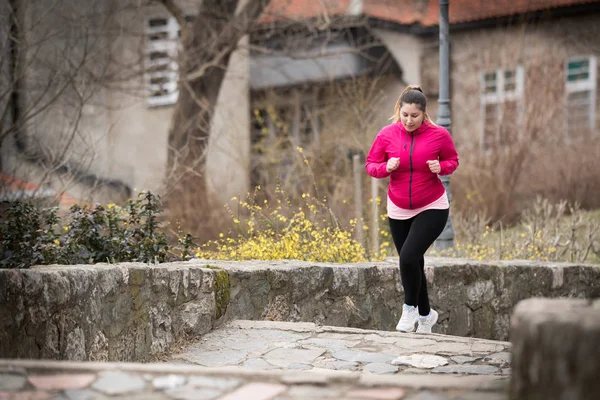 Dívka na sobě sportovní a běžela nahoru na městské pevnosti — Stock fotografie