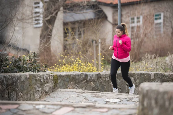 Menina vestindo roupas esportivas e correndo lá em cima na fortaleza da cidade — Fotografia de Stock