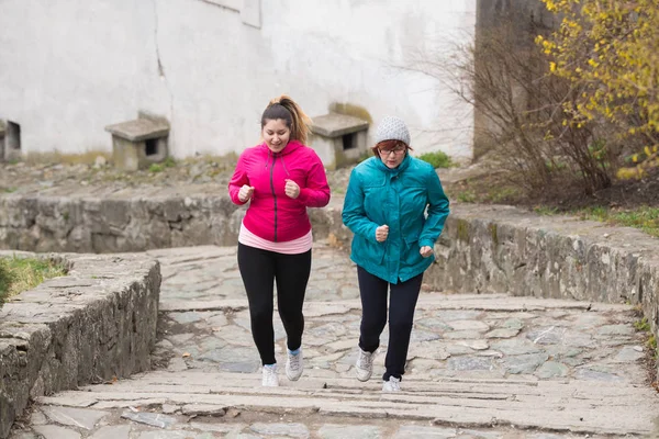 Mother and daughter wearing sportswear and running upstairs at c — Stock Photo, Image