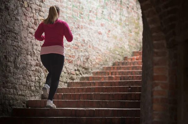 Chica usando ropa deportiva y corriendo arriba en la fortaleza de la ciudad —  Fotos de Stock