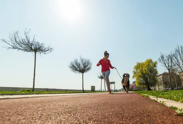 Mladá hezká dívka běží venku s její BERNSKÝ SALAŠNICKÝ PES — Stock fotografie