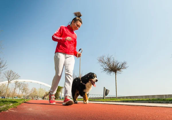 Ung vacker flicka kör utomhus med hennes Berner Sennen — Stockfoto