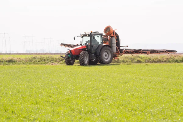 Trekker sproeien van pesticiden op tarweveld met sproeier — Stockfoto