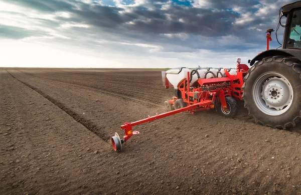 Farmář s traktorem sešlost - setí plodin na zemědělské oblasti — Stock fotografie