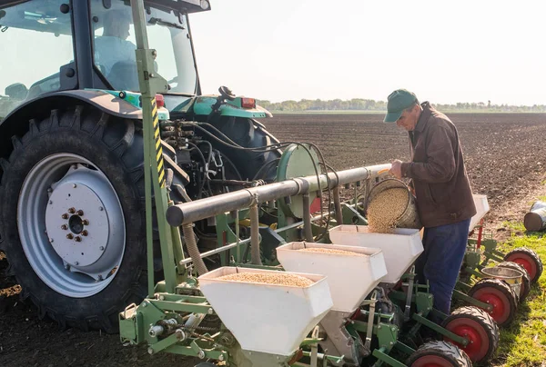 Farmář s může vylévající sójové semeno k setí plodin na agricultura — Stock fotografie