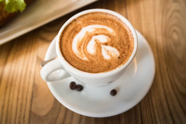 Taza de café expreso fresco con latte arte en brillante ta de madera — Foto de Stock