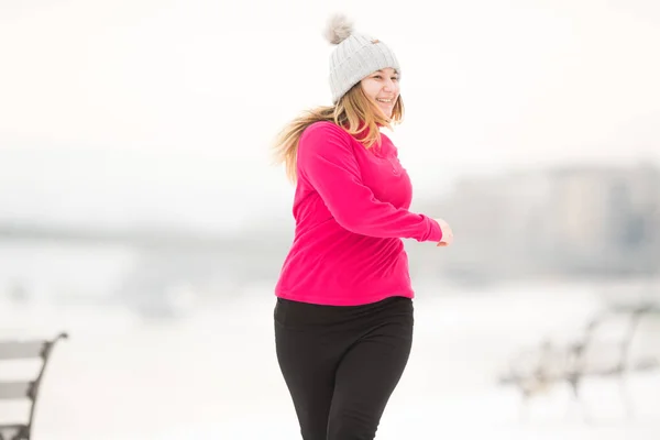 Hübsches Mädchen in Sportbekleidung und läuft bei Wind auf Schnee — Stockfoto