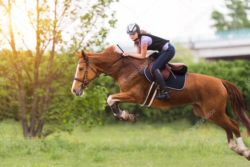 Young pretty girl riding a horse with backlit leaves behind in s