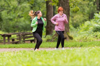 Anne ve kızı spor giyim giymek ve orman çalıştırmak için 