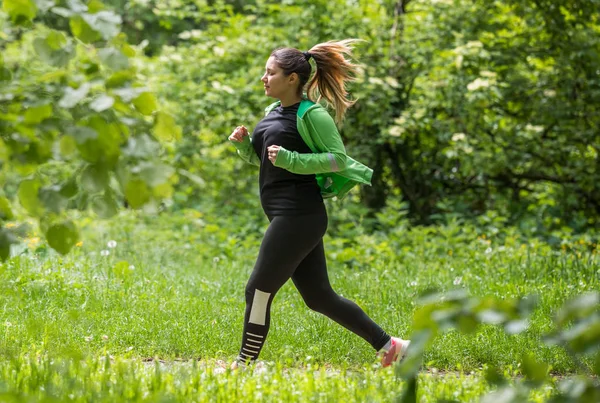Girl wearing sportswear and running in forest at mountain — Stock Photo, Image