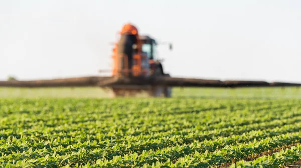 Trator pulverizando campo de soja na primavera — Fotografia de Stock