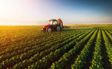 Tractor spraying soybean field at spring clipart