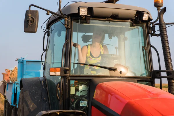 Schöne, junge Bäuerin fährt Traktor — Stockfoto