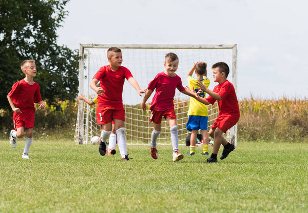 Детский футбол - детские футболисты празднуют после гола
