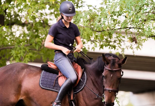 Young pretty girl riding a horse with backlit leaves behind — Stock Photo, Image