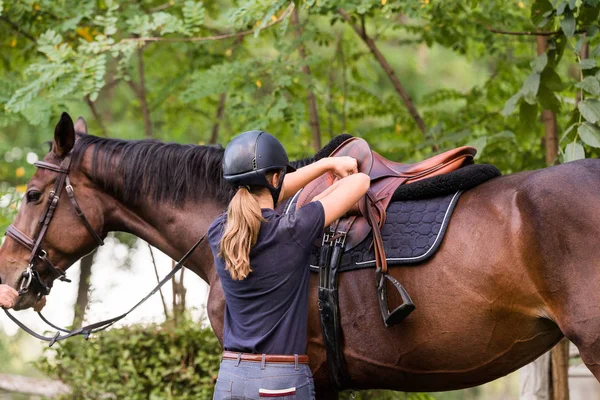 Chica joven preparando caballo para montar —  Fotos de Stock