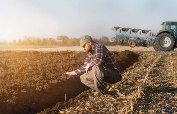 Молодий фермер виганяє посаджену пшеницю, поки трактор оранює — стокове фото
