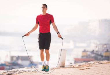 Genç adam giyiyor spor giyim sonbahar sırasında quay, ip atlama