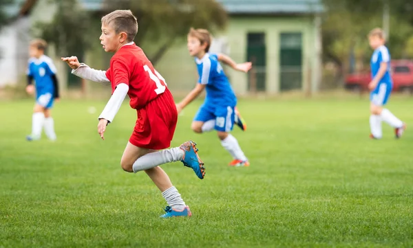 Ragazzo calci calcio sul campo sportivo — Foto Stock