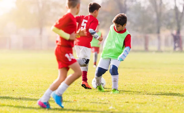 Хлопчик штовхає футбол на спортивне поле — стокове фото