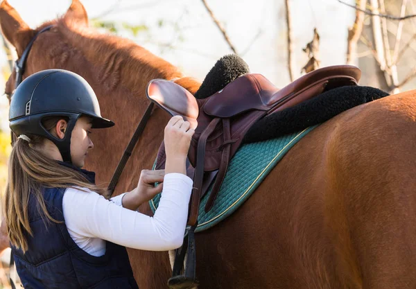 Young pretty girl preparing horse for riding — Stock Photo, Image