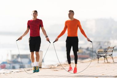 Yakışıklı genç erkek spor giyim giymek ve quay, ip atlama