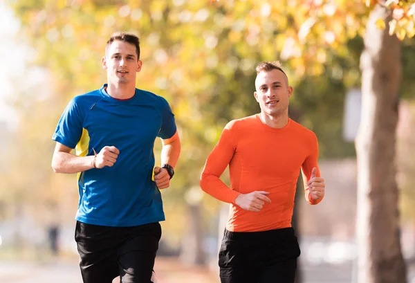 Gut aussehende junge Männer in Sportbekleidung und laufen am Kai während — Stockfoto