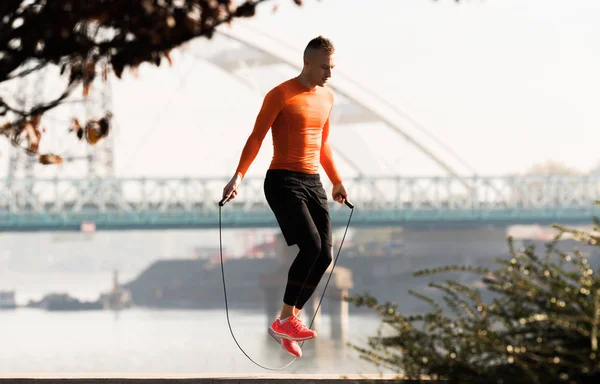 Schöner junger Mann in Sportbekleidung und Springseil am Kai — Stockfoto