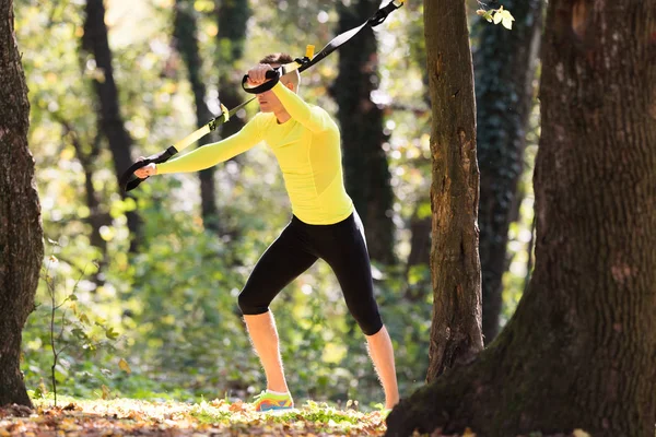 Knappe jonge mannen het dragen van sportkleding en oefenen in het bos een — Stockfoto