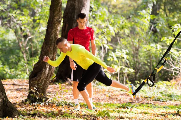 Guapos jóvenes con ropa deportiva y ejercicio en el bosque a —  Fotos de Stock