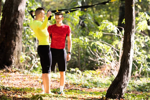 Guapos jóvenes con ropa deportiva y ejercicio en el bosque a —  Fotos de Stock