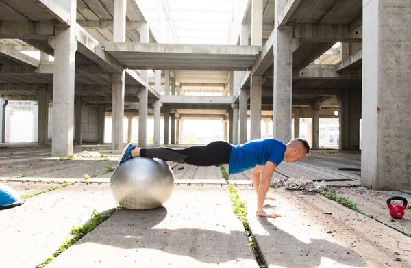 Jonge knappe atleet man doen pushups met zilveren pilates bal — Stockfoto