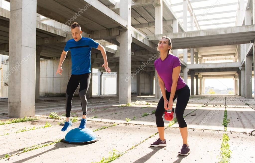Young athlete couple doing exercise  in an old abandoned buildin