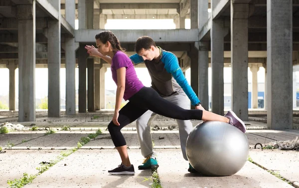 Young athlete couple doing exercise  in an old abandoned buildin — Stock Photo, Image