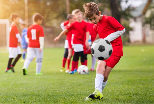 Ragazzo calci calcio sul campo sportivo — Foto Stock