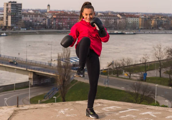 Молодая девушка в боксёрских перчатках наносит удар - боевые искусства — стоковое фото