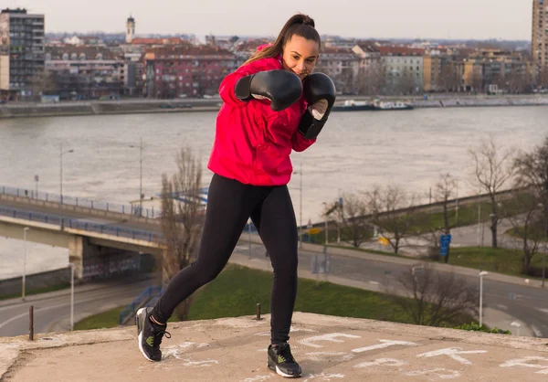 Jovem usando luvas de boxe dando um soco - artes marciais — Fotografia de Stock