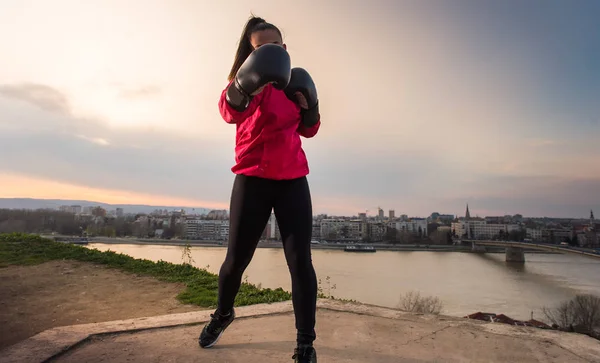 Chica joven con guantes de boxeo lanzando un puñetazo - artes marciales —  Fotos de Stock