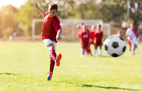 Ragazzo calci calcio sul campo sportivo — Foto Stock