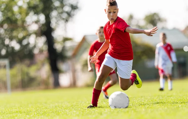 Jongen schoppen Voetbal op het sportveld — Stockfoto