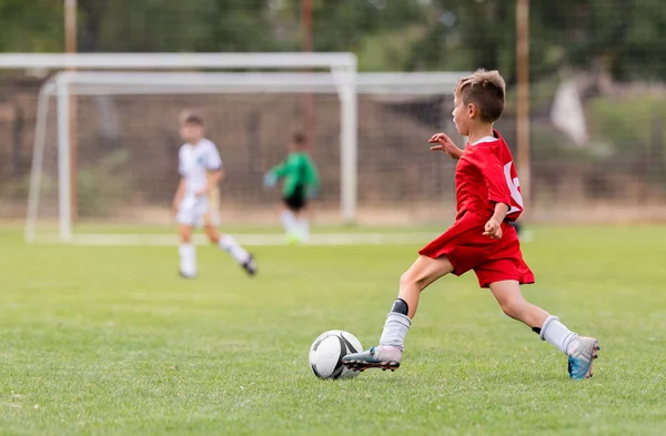 Chico pateando fútbol en el campo de deportes —  Fotos de Stock