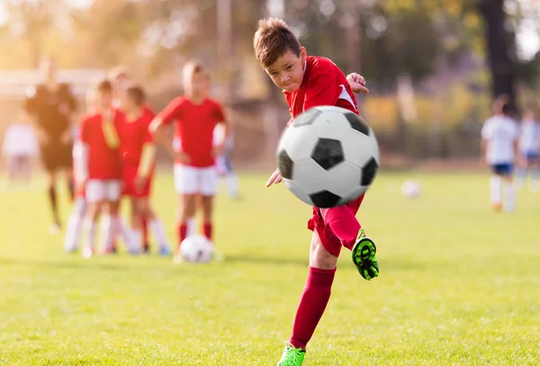 Ragazzo calci calcio sul campo sportivo — Foto Stock