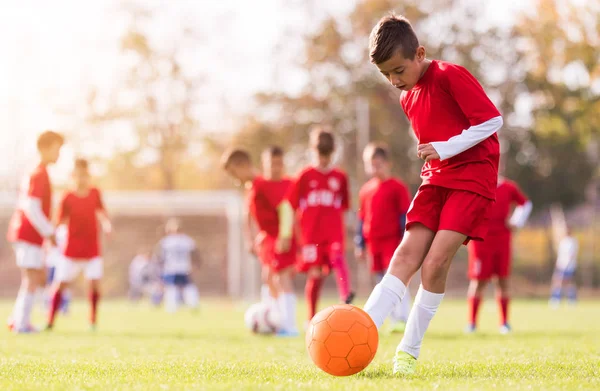 Menino chutando futebol no campo de esportes — Fotografia de Stock