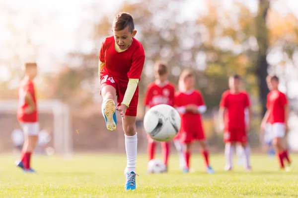 Chico pateando fútbol en el campo de deportes —  Fotos de Stock